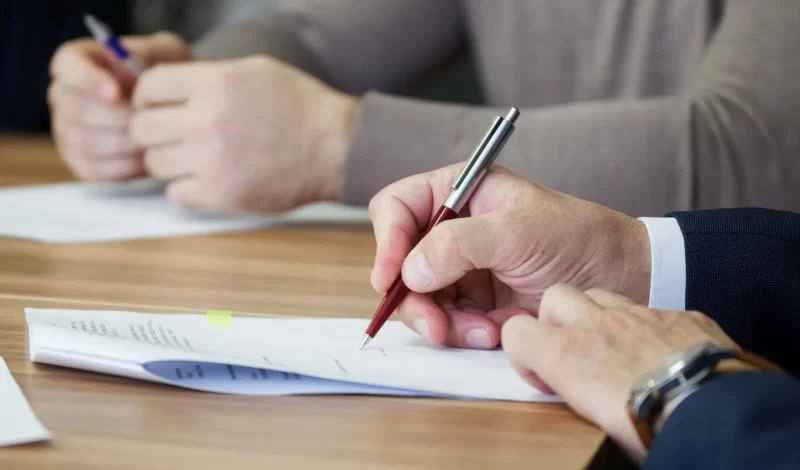 A person writing on a document at a desk