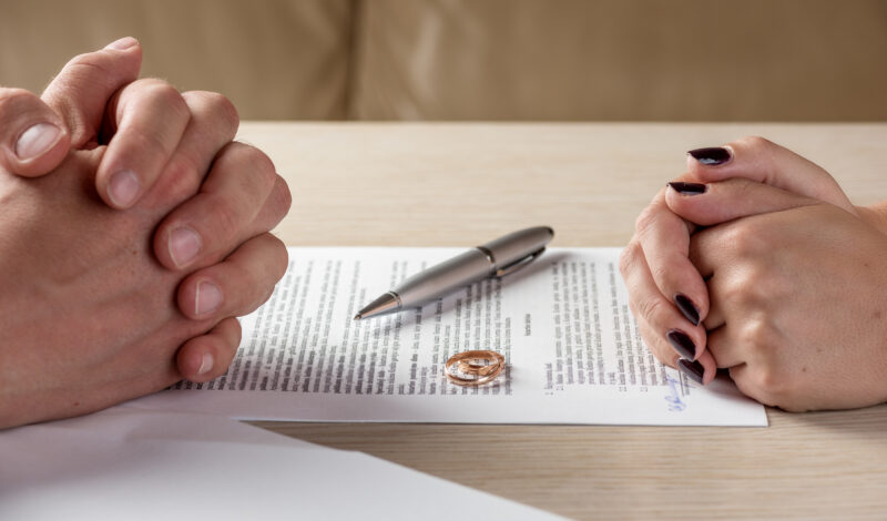 Hands of wife and husband signing divorce documents