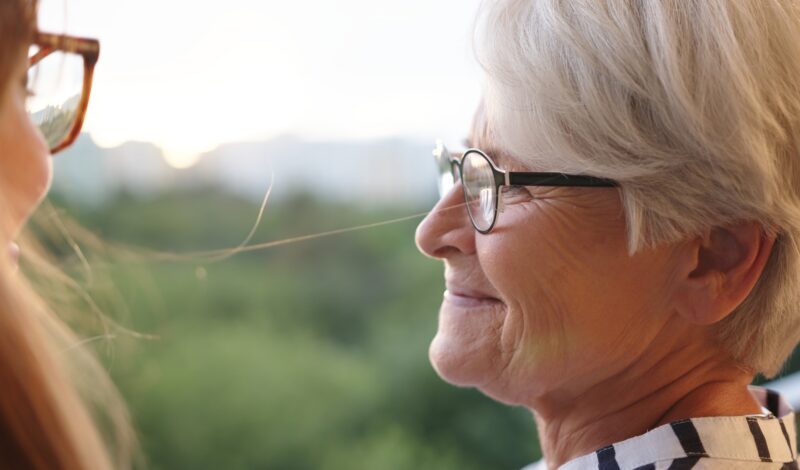 Close up shot of senior mother and adult daughter looking in at each other on the balcony
