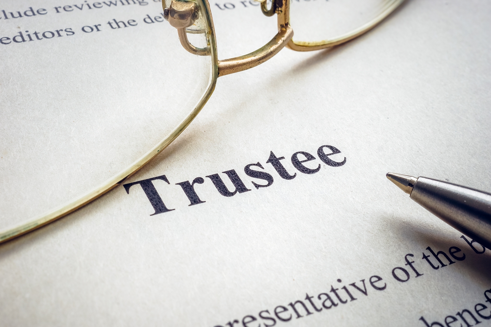 Word trustee near glasses and a pen.