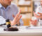 A gavel on a table in front of an arguing couple