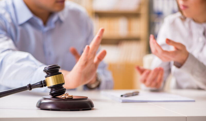 A gavel on a table in front of an arguing couple