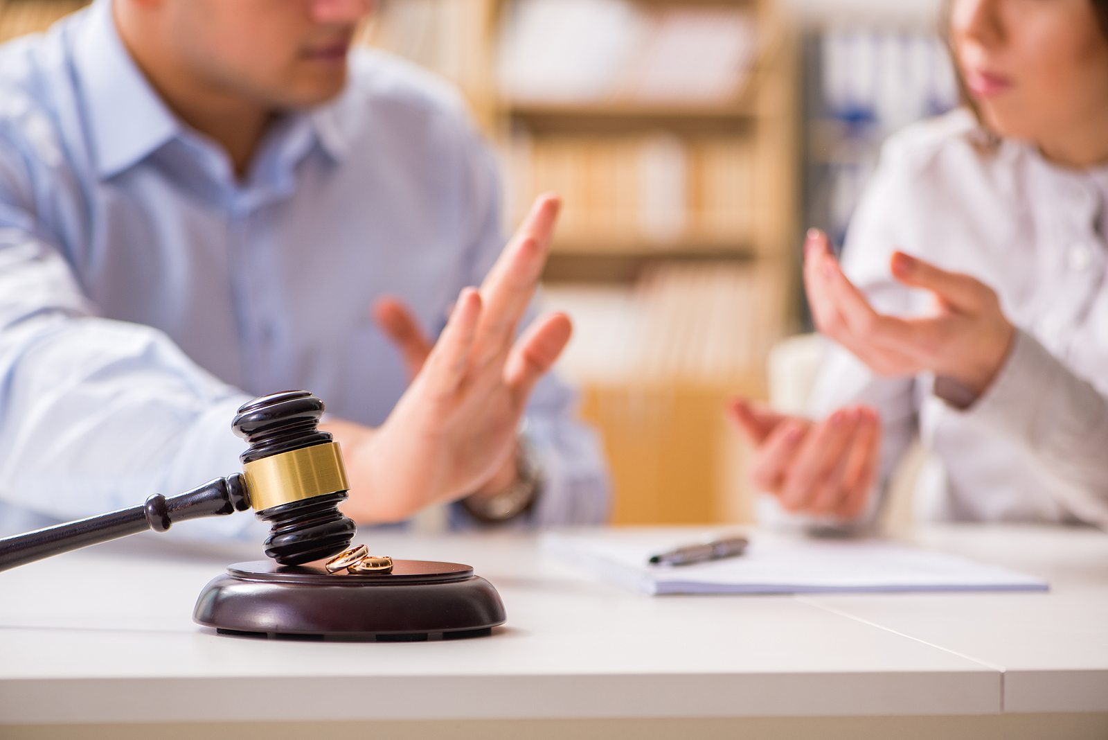 A gavel on a table in front of an arguing couple